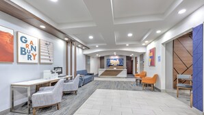 A modern lobby with a reception desk, seating area, and artwork on the walls.