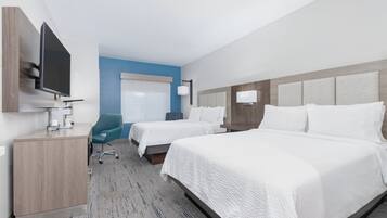 A hotel room with two beds, a desk, a TV, and a chair.