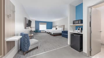 A hotel room with two beds, a desk, a microwave, and a refrigerator.
