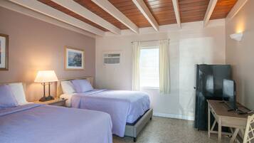 Habitación de hotel con dos camas, un escritorio, un televisor y una ventana con cortinas.