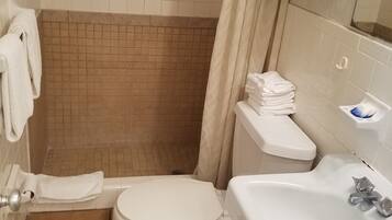 A small bathroom with a toilet, sink, and shower area.