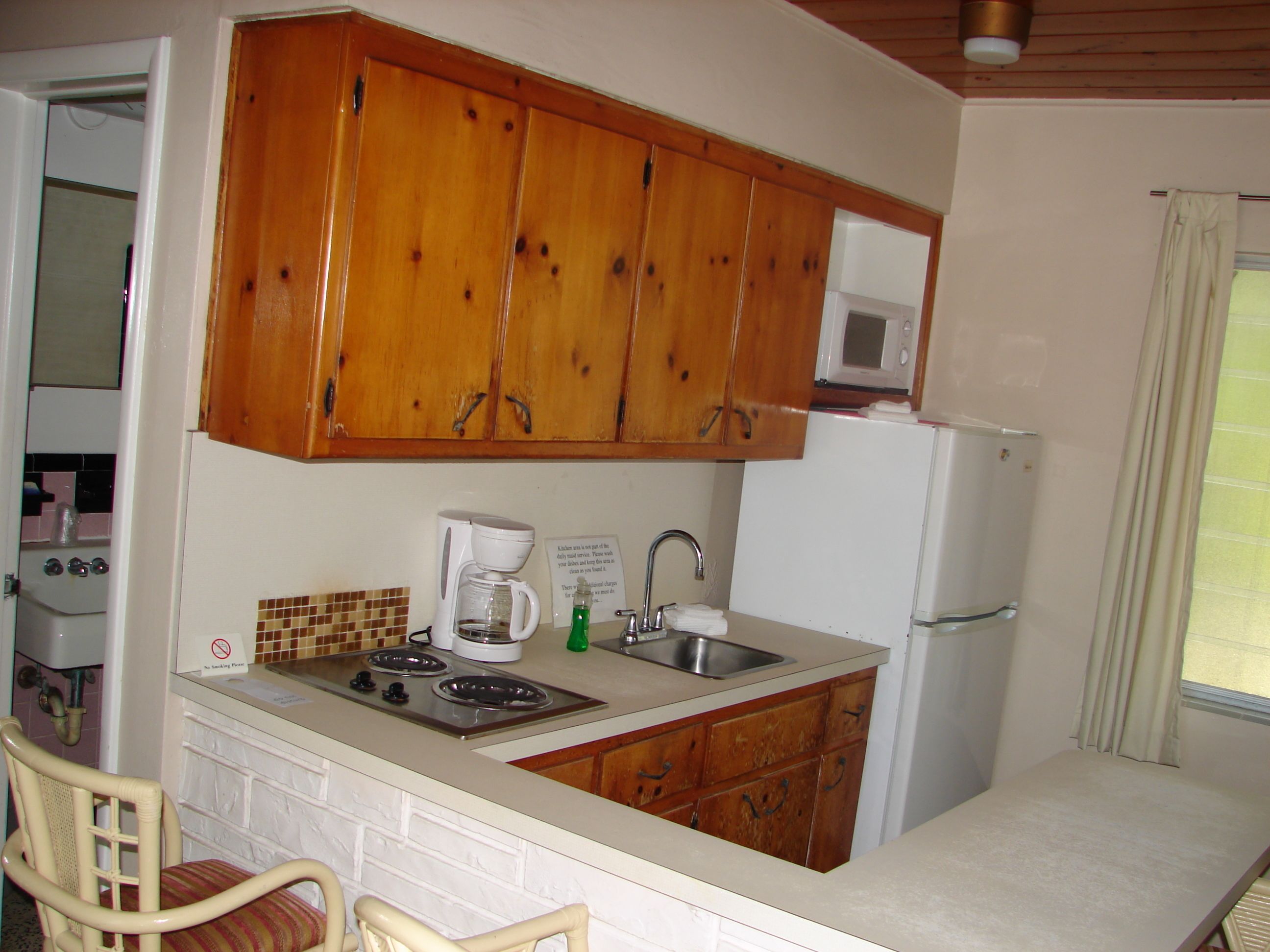 A compact kitchen with wooden cabinets, a microwave, a sink, and a stove.