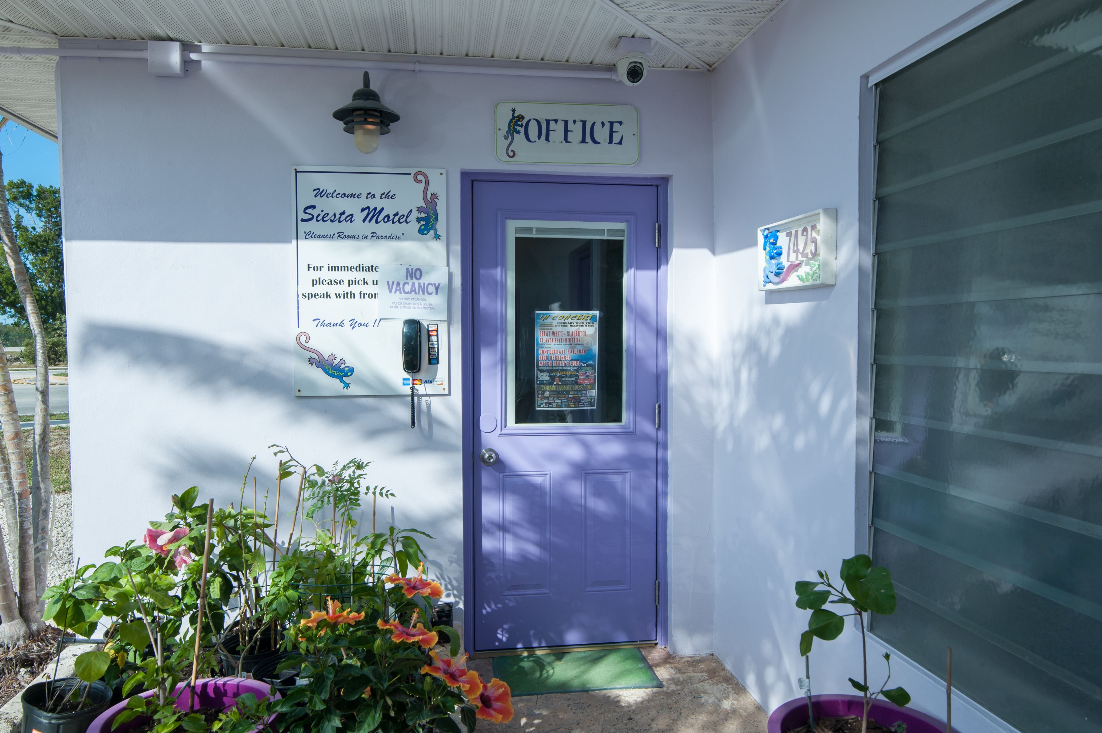 En lilla dør med teksten "OFFICE" foran en bygning, hvor der også er et velkomstskilt til Seesta Motel.