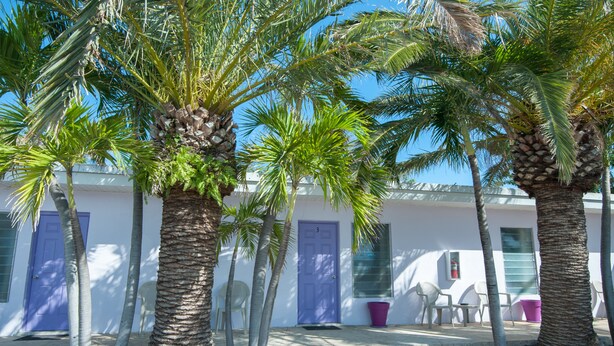 Un edificio de fachada blanca, con puertas moradas y un pequeño patio con sillas y una mesa.