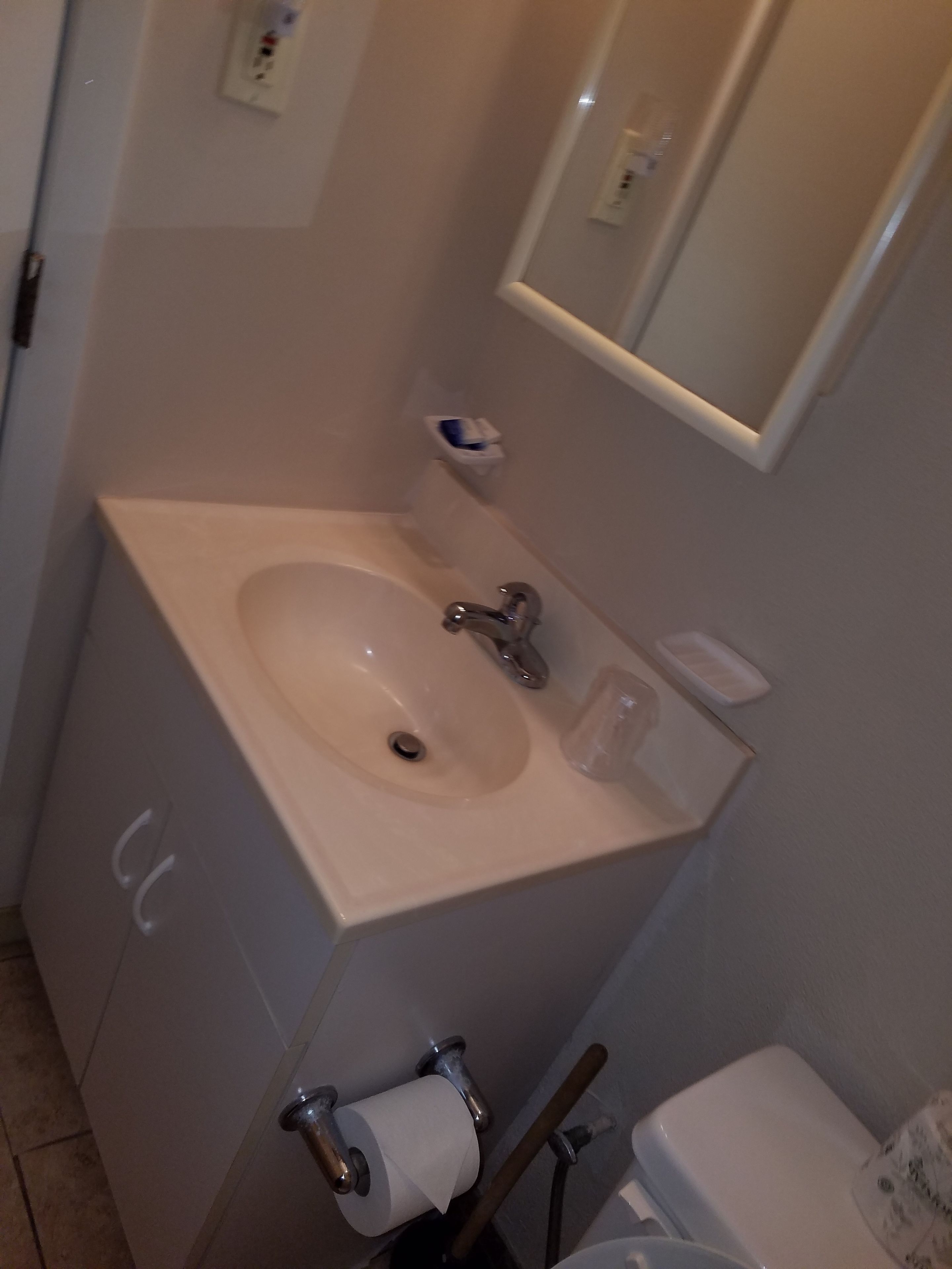 Baño con lavamanos, espejo, inodoro y secador de manos.