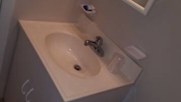 Baño con lavamanos, espejo, inodoro y secador de manos.
