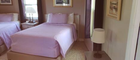 A bedroom with two beds, a nightstand with a lamp, and a framed picture on the wall.