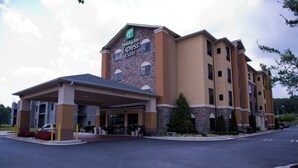 A Holiday Inn Express & Suites hotel with a covered entrance, a parking lot, and a clear sky.