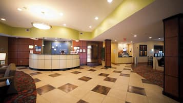 A hotel lobby with a reception desk, check-in counters, and a seating area.