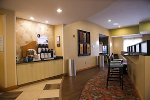 A hotel reception area with a coffee station, seating area, and a trash bin. - Holiday Inn Express & Suites Atlanta East – Lithonia by IHG (Lithonia)