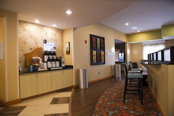 A hotel reception area with a coffee station, seating area, and a trash bin. - Holiday Inn Express & Suites Atlanta East – Lithonia by IHG (Lithonia)