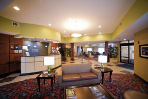 Um saguão de hotel com balcão de recepção, área de estar e balcão de check-in.