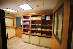A snack bar with shelves stocked with various food items and a chalkboard menu. - Holiday Inn Express & Suites Atlanta East – Lithonia by IHG (Lithonia)