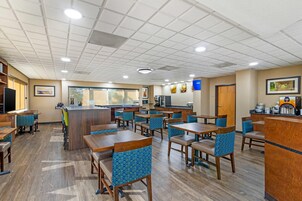 Un hall de hotel con varias zonas de estar, un mostrador de recepción y una cocina.