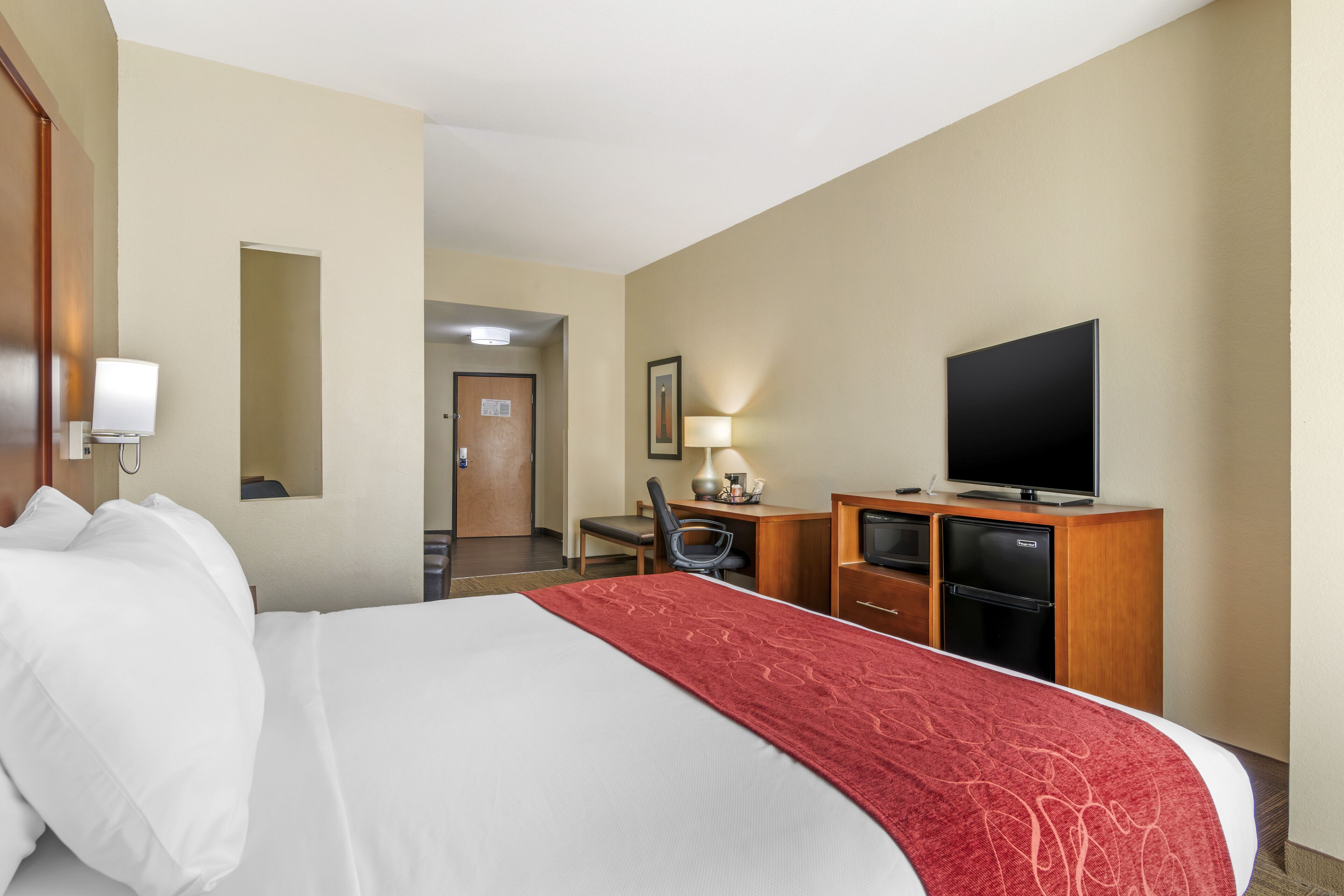 A hotel room with a bed, a desk, a television, and a mirror.