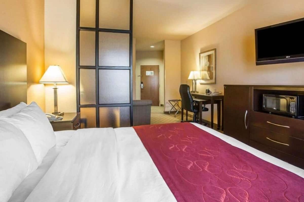 A hotel room with a bed, desk, chair, and a television on the wall.
