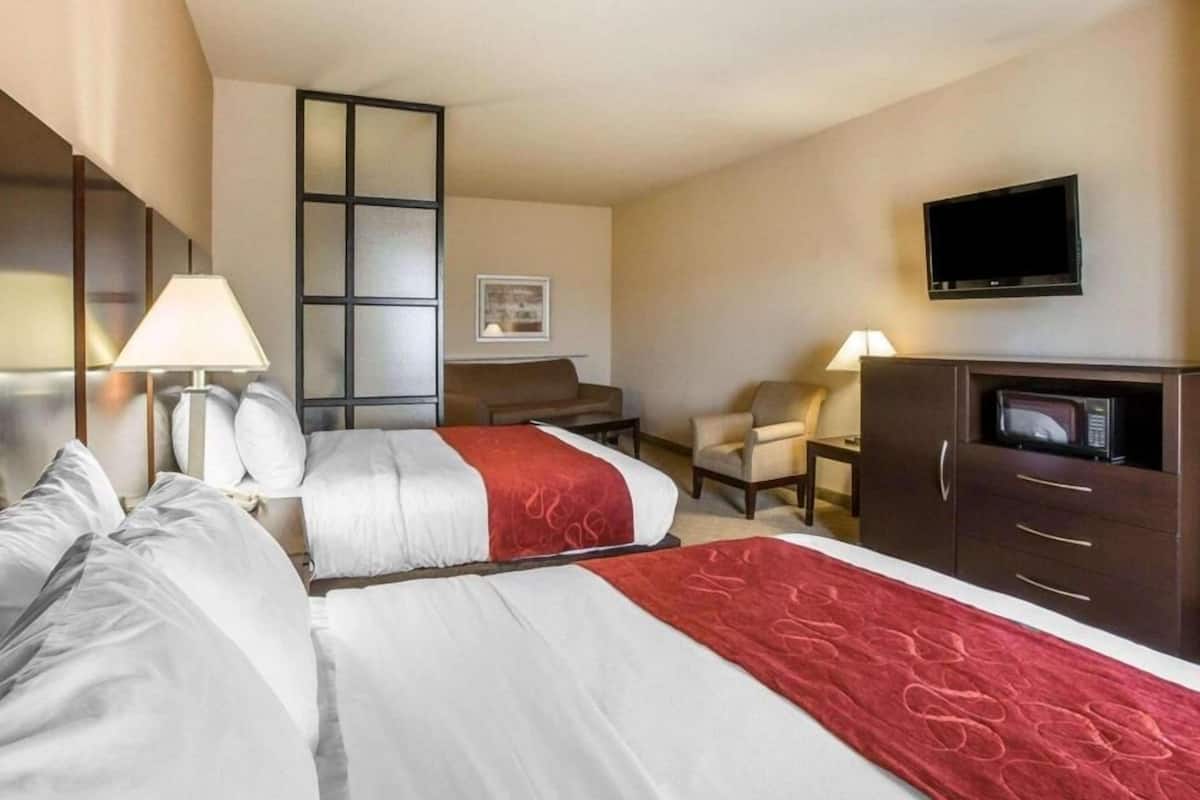 Ein Hotelzimmer mit zwei Betten, einem Schreibtisch, einem Stuhl, einem Fernseher und einer Mikrowelle.