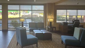 A hotel lobby with seating, a desk, and large windows offering a view of the parking area. - Comfort Suites Macon Northwest (Macon)