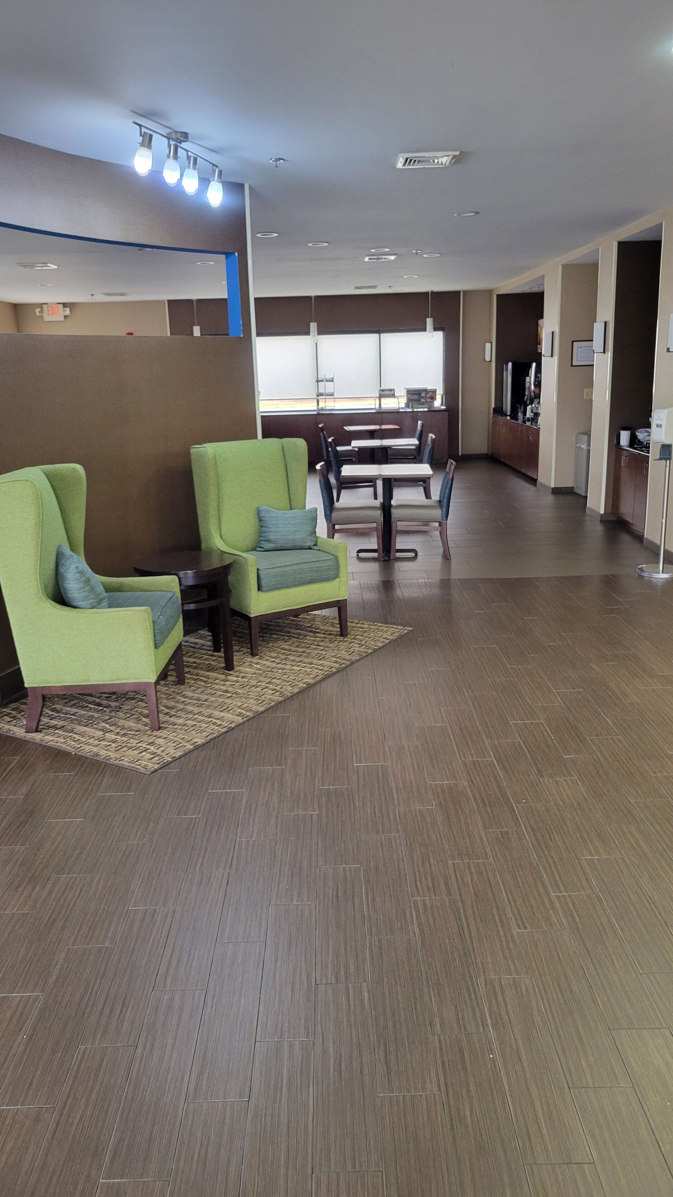 Un espace d’accueil avec des fauteuils verts, une petite table et un comptoir de réception.