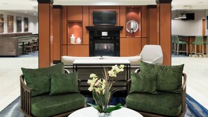 Un moderno vestíbulo de hotel con chimenea, zona de estar y bar.
