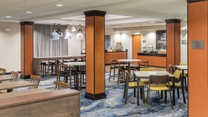 Un comedor de hotel con varias mesas y sillas, una barra y un mostrador con una máquina de café.