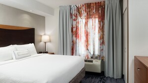 Habitación de hotel con una cama grande, una mesita de noche con lámpara, un calefactor y un aparador de madera.