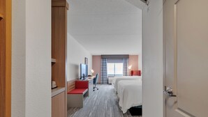 A hotel room with a desk, two beds, a red chair, and a window with curtains. - Hilton Garden Inn Myrtle Beach/Coastal Grand Mall (Myrtle Beach)