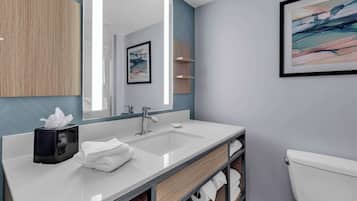 A modern bathroom with a large mirror, two sinks, a toilet, and a towel rack.
