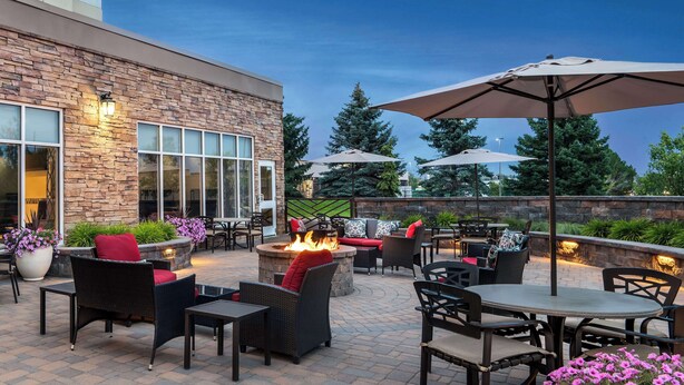 An outdoor patio area with stone walls, wicker furniture, and a fire pit.