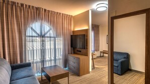 A modern hotel room with a large window, a sofa, a coffee table, a TV, and a mirror. - Holiday Inn Express Reno Airport by IHG (Reno)