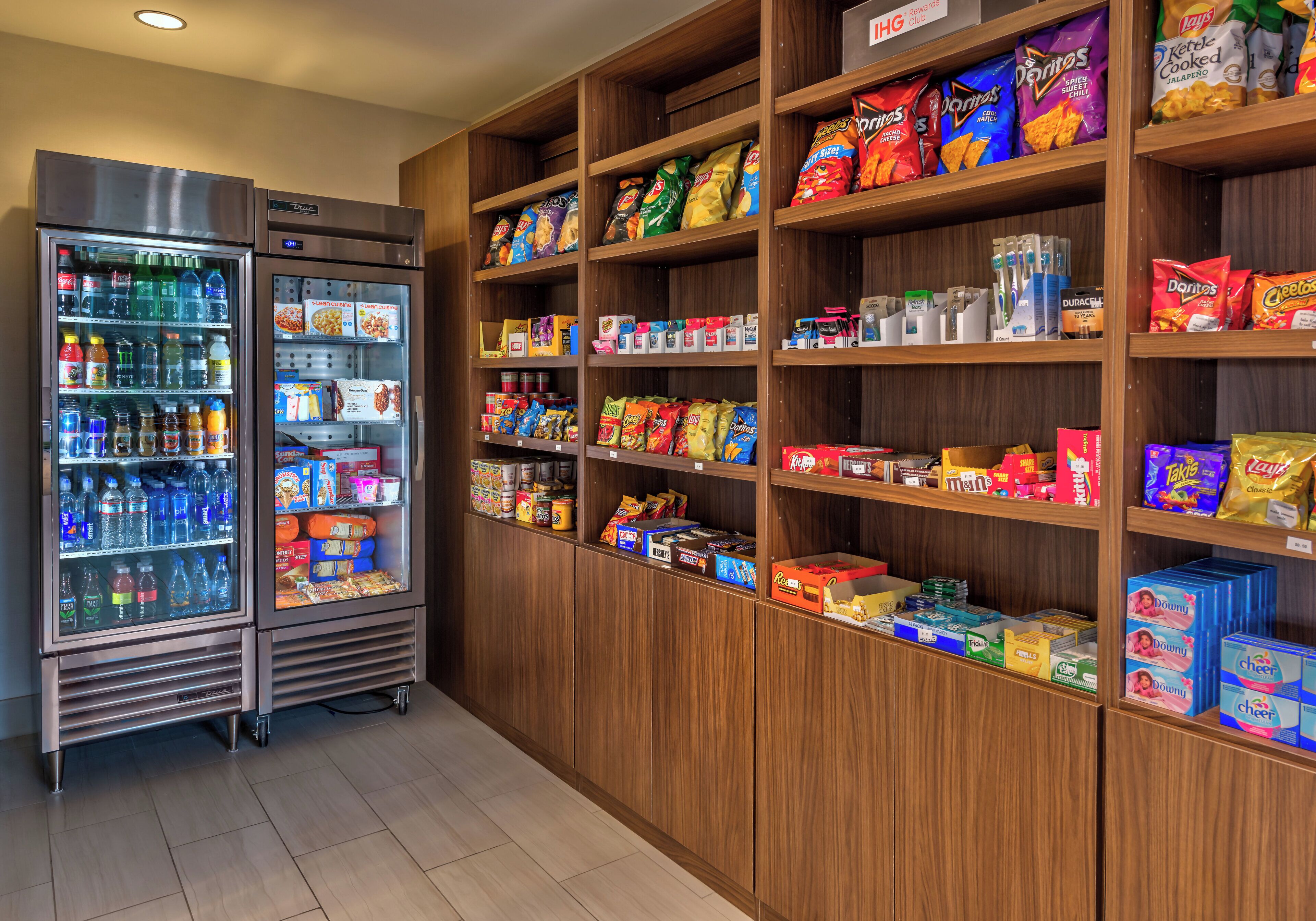 A vending machine stocked with various beverages and snacks, surrounded by shelves with packaged food items.