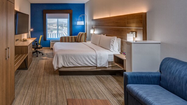 A hotel room with a bed, a desk, a chair, a sofa, and a TV. - Holiday Inn Express Reno Airport by IHG (Reno)