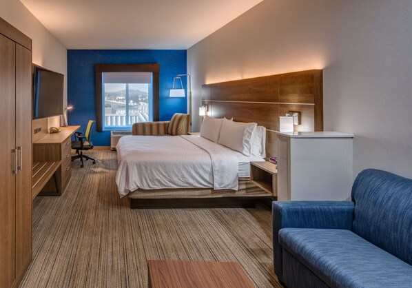 A hotel room with a bed, a desk, a chair, a sofa, and a TV. - Holiday Inn Express Reno Airport by IHG (Reno)