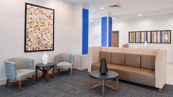 A lobby with a reception desk, seating area, and artwork on the walls.