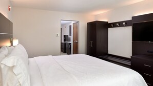 A hotel room with a large bed, a wardrobe, a television, and a mirror. - Holiday Inn Express & Suites Pueblo North by IHG (Pueblo)