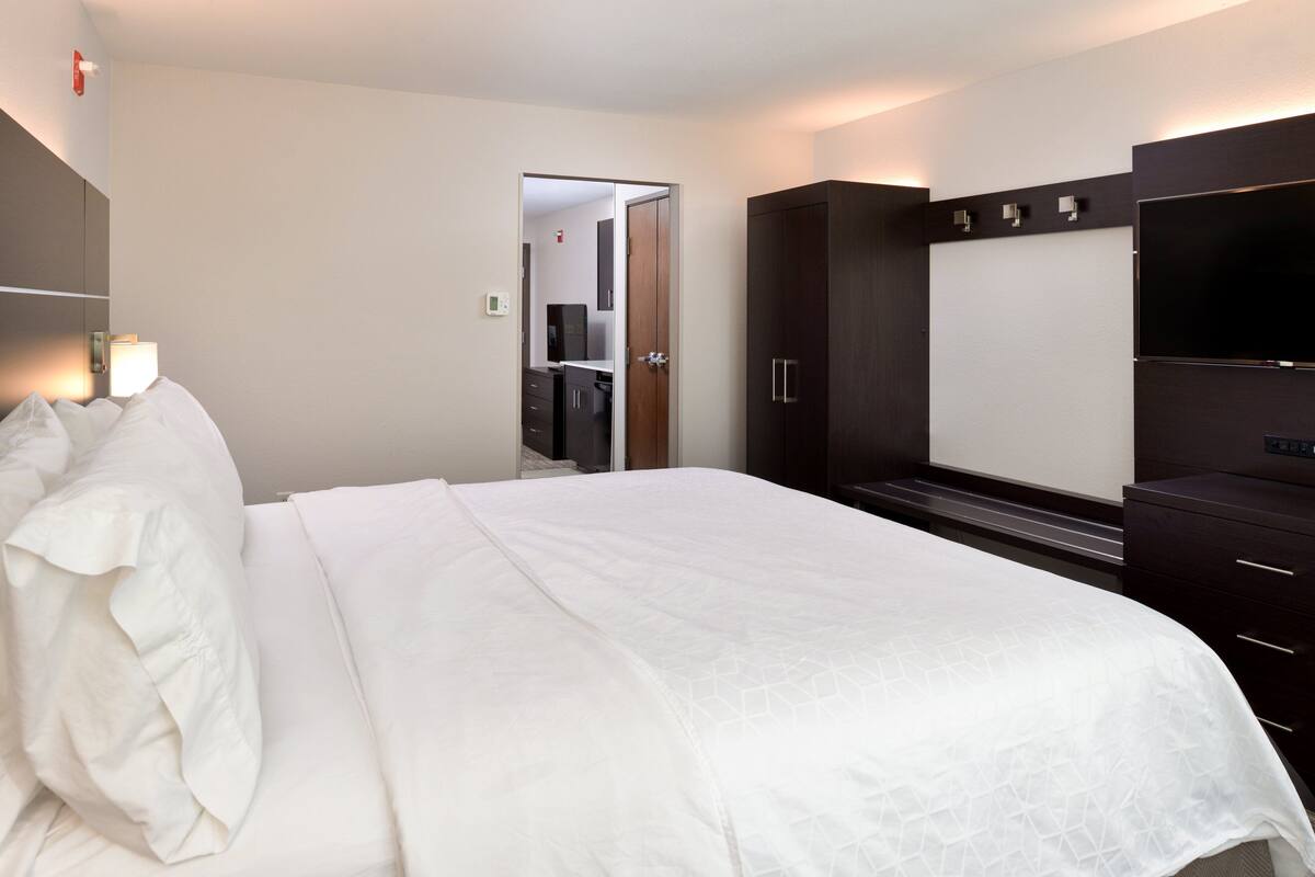 A hotel room with a large bed, a wardrobe, a television, and a mirror.