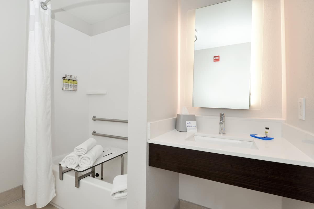 A modern bathroom with a shower, a sink, and a towel rack.