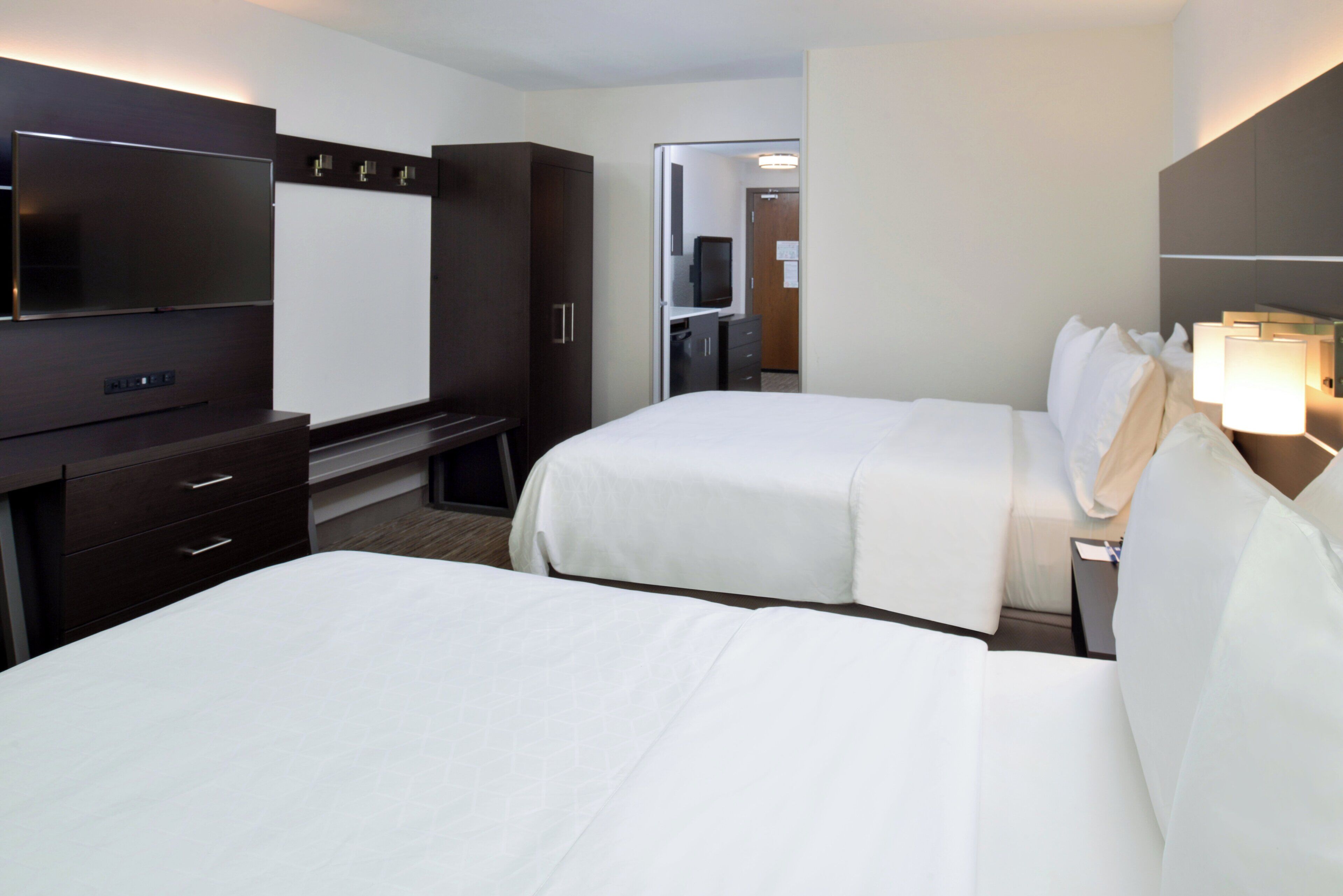 Une chambre d’hôtel avec deux lits, une télévision, un bureau et une armoire.