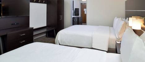 Une chambre d’hôtel avec deux lits, une télévision, un bureau et une armoire.