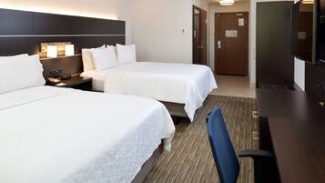 Een hotelkamer met twee bedden, een bureau, een stoel en een televisie.
