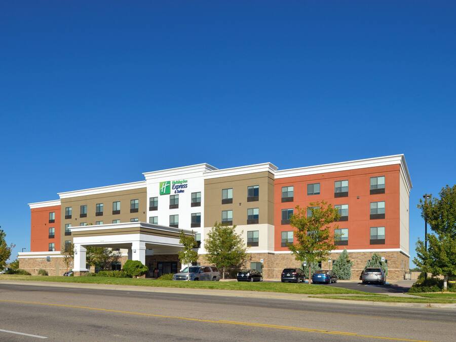 Ein Holiday Inn Express Gebäude mit einem zentralen Eingang, mehreren Stockwerken und einem Parkplatz mit einigen Autos.