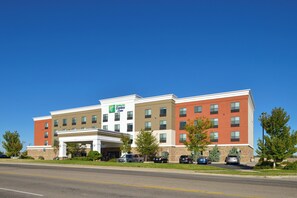 Un bâtiment de la chaîne Holiday Inn Express, doté d’une entrée centrale, de plusieurs étages et d’un parking contenant plusieurs voitures.