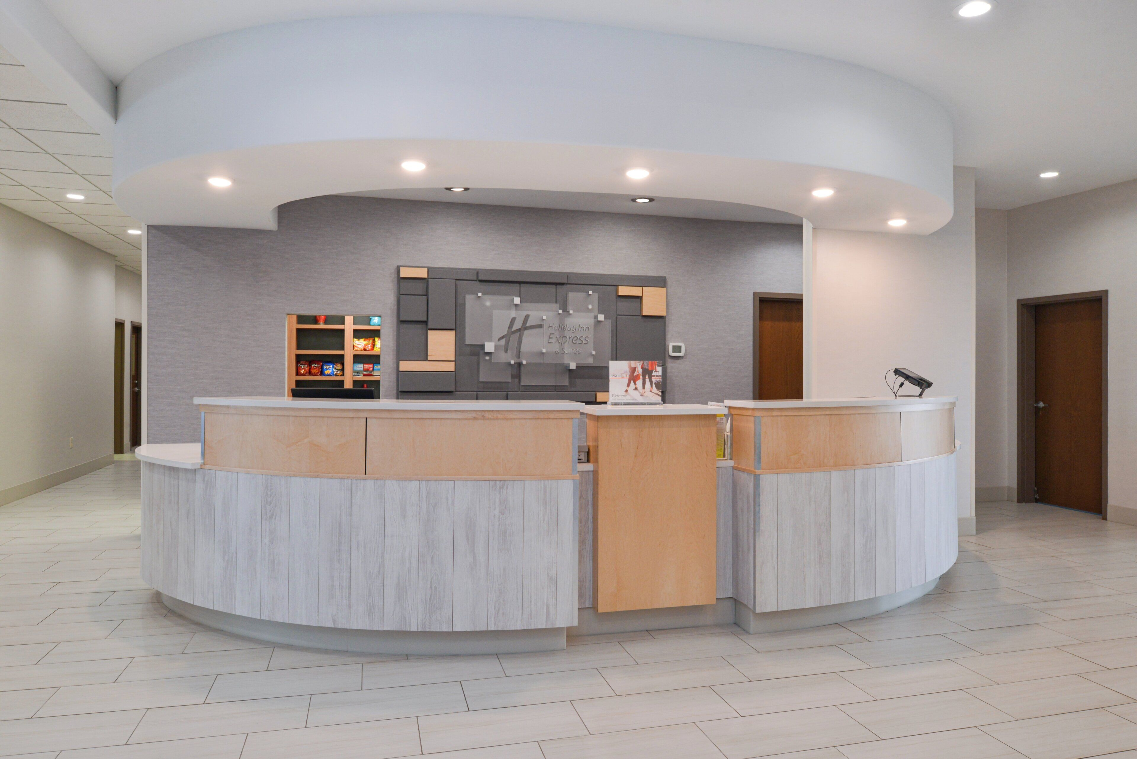 A reception area with a curved counter, a wall-mounted information board, and a small shelf with snacks.