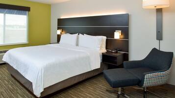 Een hotelkamer met een groot bed, een nachtkastje, een stoel en een wandlamp.
