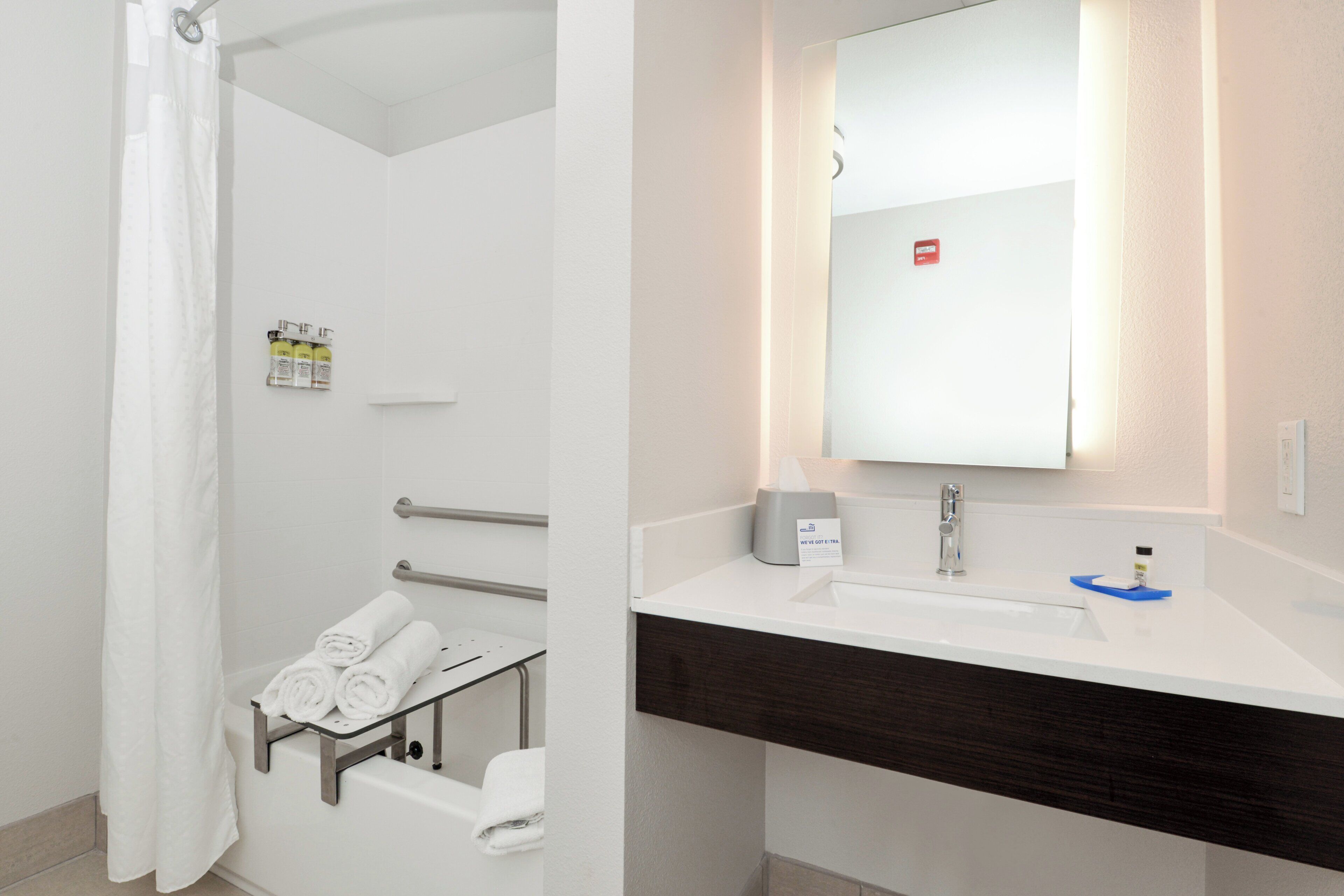 A bathroom with a shower, a towel rack, a sink, and a mirror.