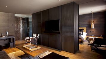 A modern living room with a flat-screen TV, a wooden coffee table, and a leather sofa.