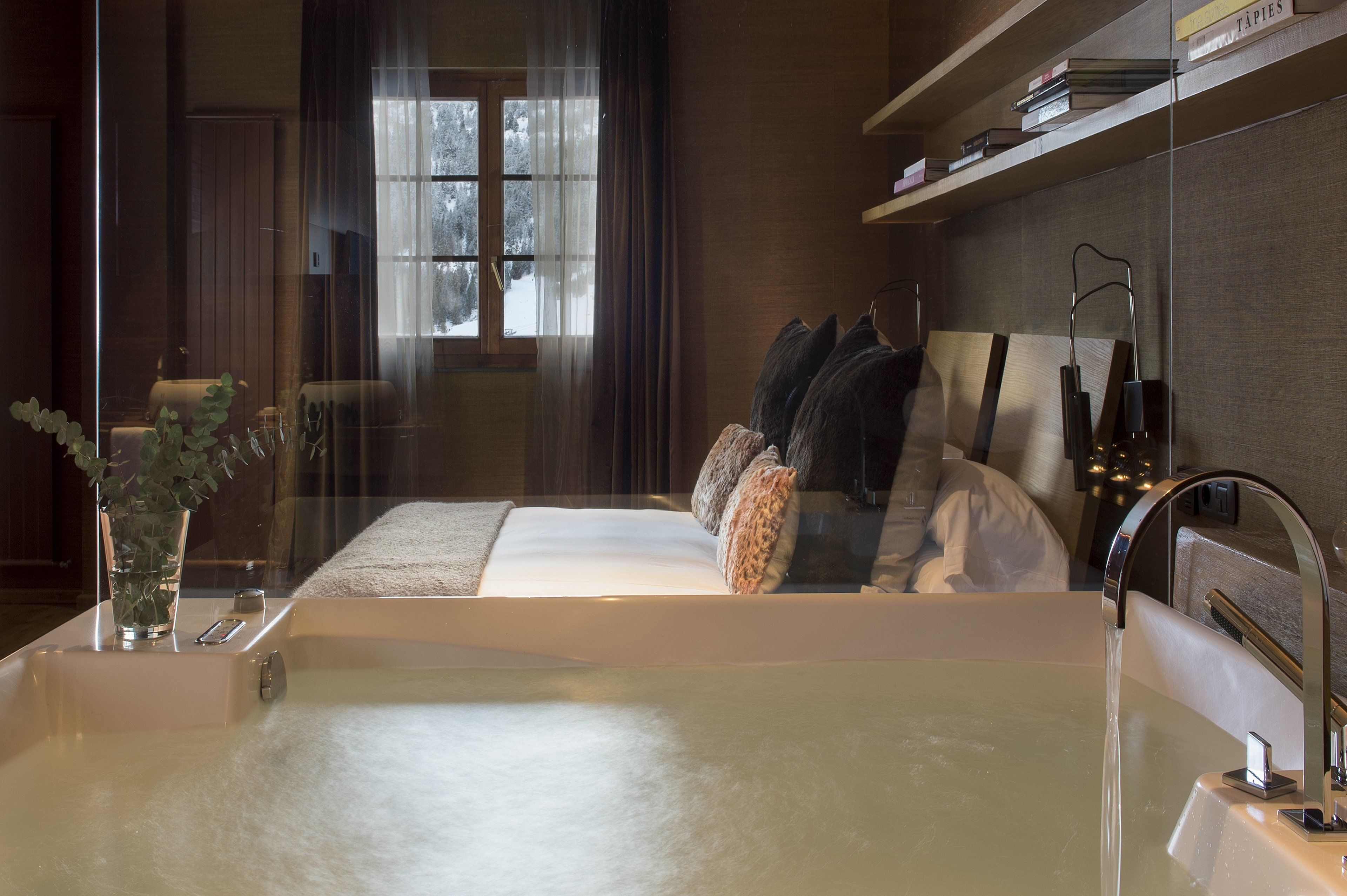 Un baño moderno con una bañera grande, un box de ducha de vidrio y una mesita de noche con un florero.