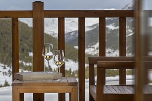 A wooden table with two wine glasses and a book titled "VELAZQUEZ" on a deck with a mountain view. - Grau Roig Andorra Boutique Hotel & Spa (Grau Roig)