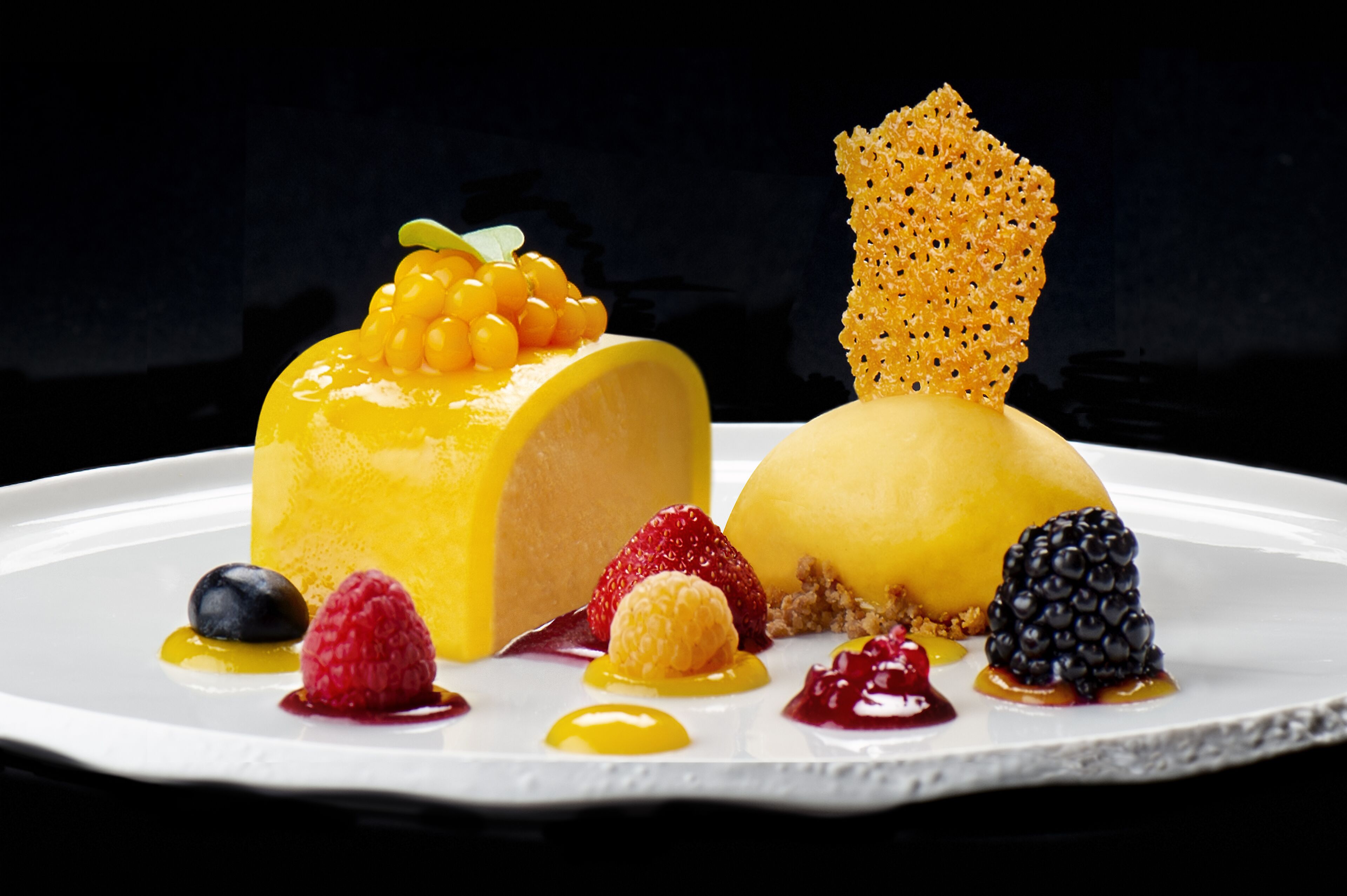 A dessert with a yellow base, berries, and a honeycomb-like topping.