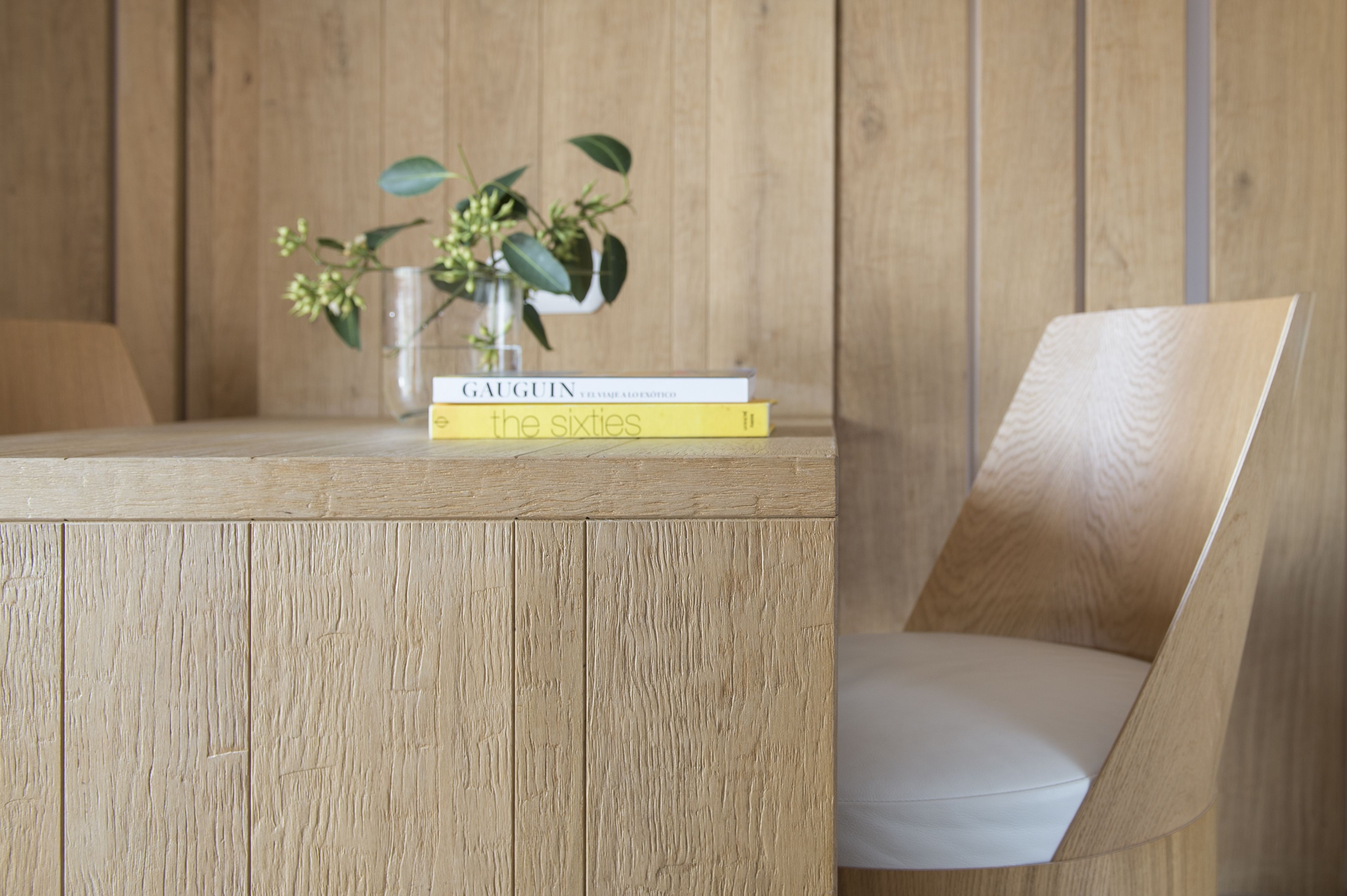A wooden table with two books and a small vase with flowers.